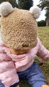 芝生の上で帽子をかぶって座る幼児の写真