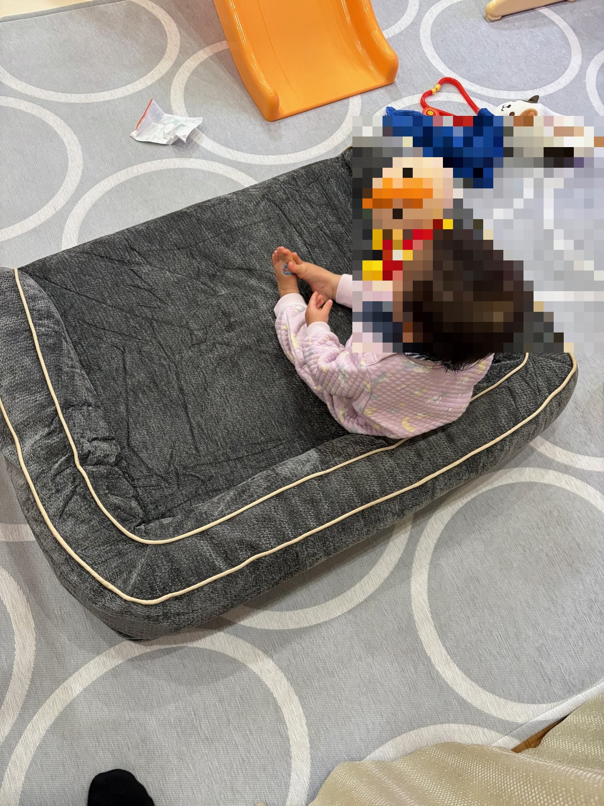 ソファカバーをかけたソファに座る赤ちゃんとアンパンマン人形